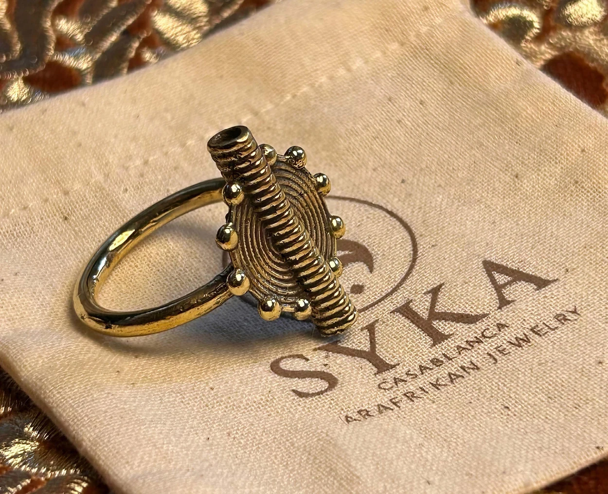 Une bague SYKA sur son pochon de marque, détail du relief et des lignes.
